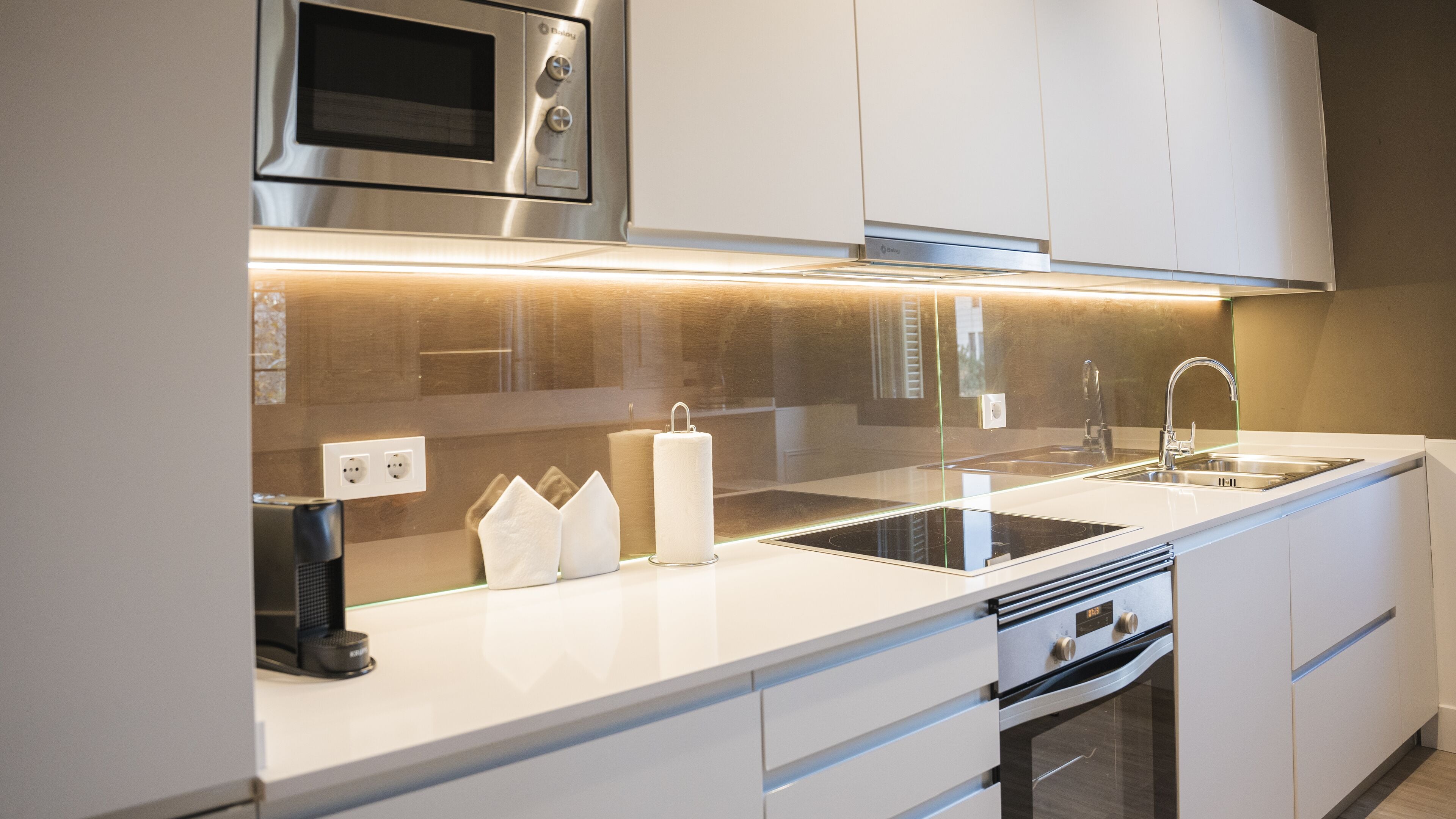 Una cocina moderna con electrodomésticos de acero inoxidable, un lavamanos doble y un horno empotrado.