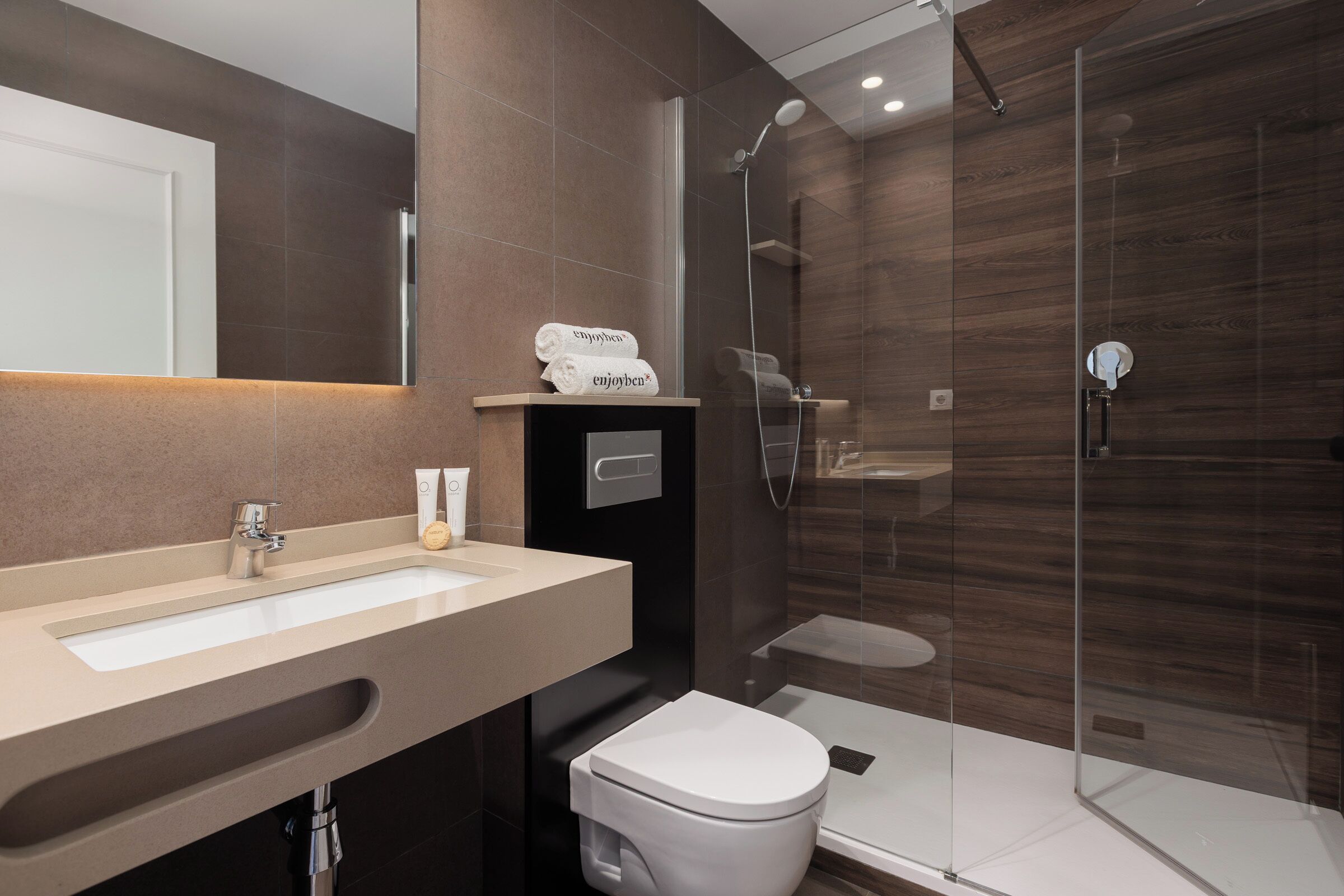 Un baño moderno con un lavamanos grande, un inodoro y una ducha con cerramiento de vidrio.