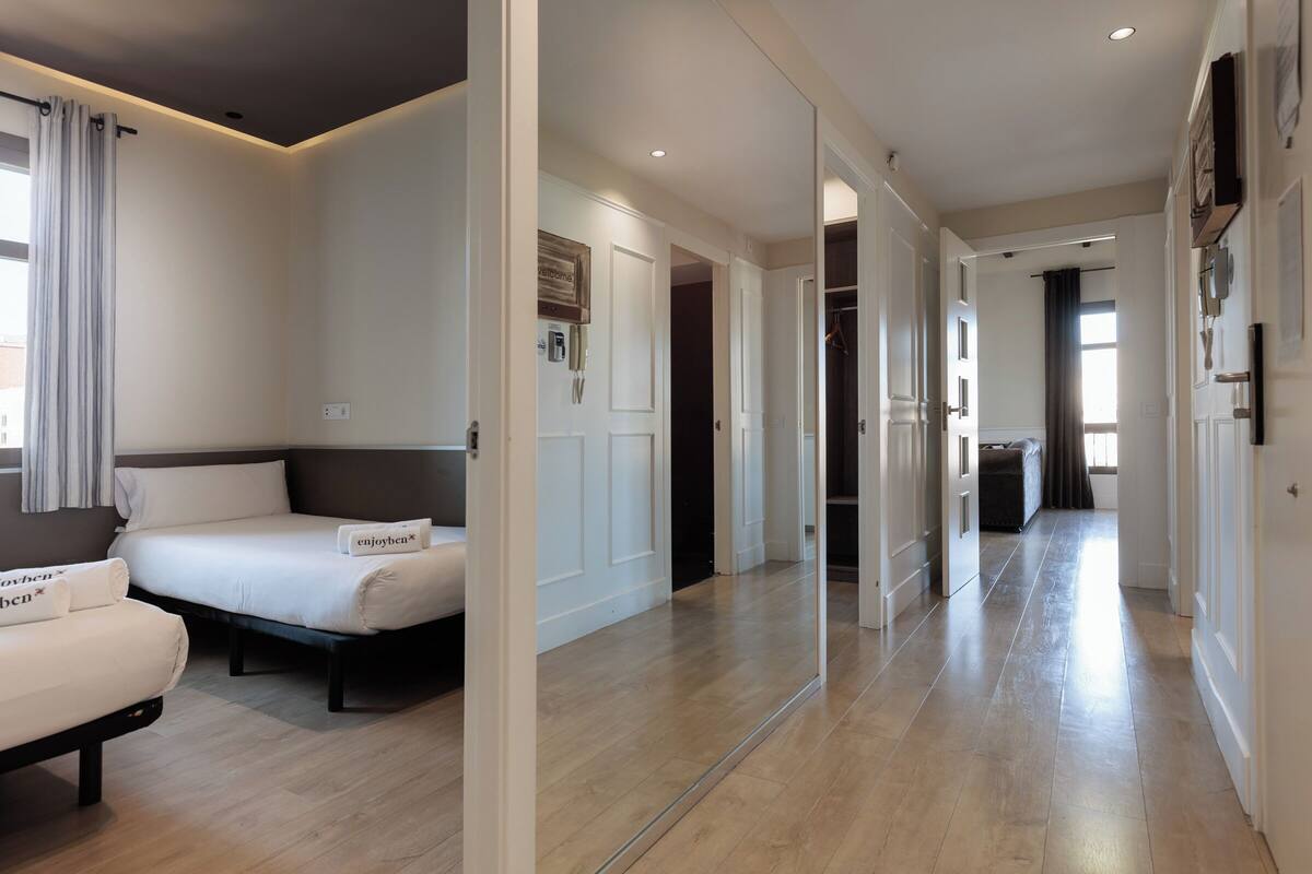 A modern hotel room with a large bed, a sofa, and a mirror.