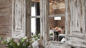 A rustic room with exposed brick walls, a distressed white wooden door, and a view of a dining area with a table and chairs. - Enjoybcn Miro Apartments (Barcelona)
