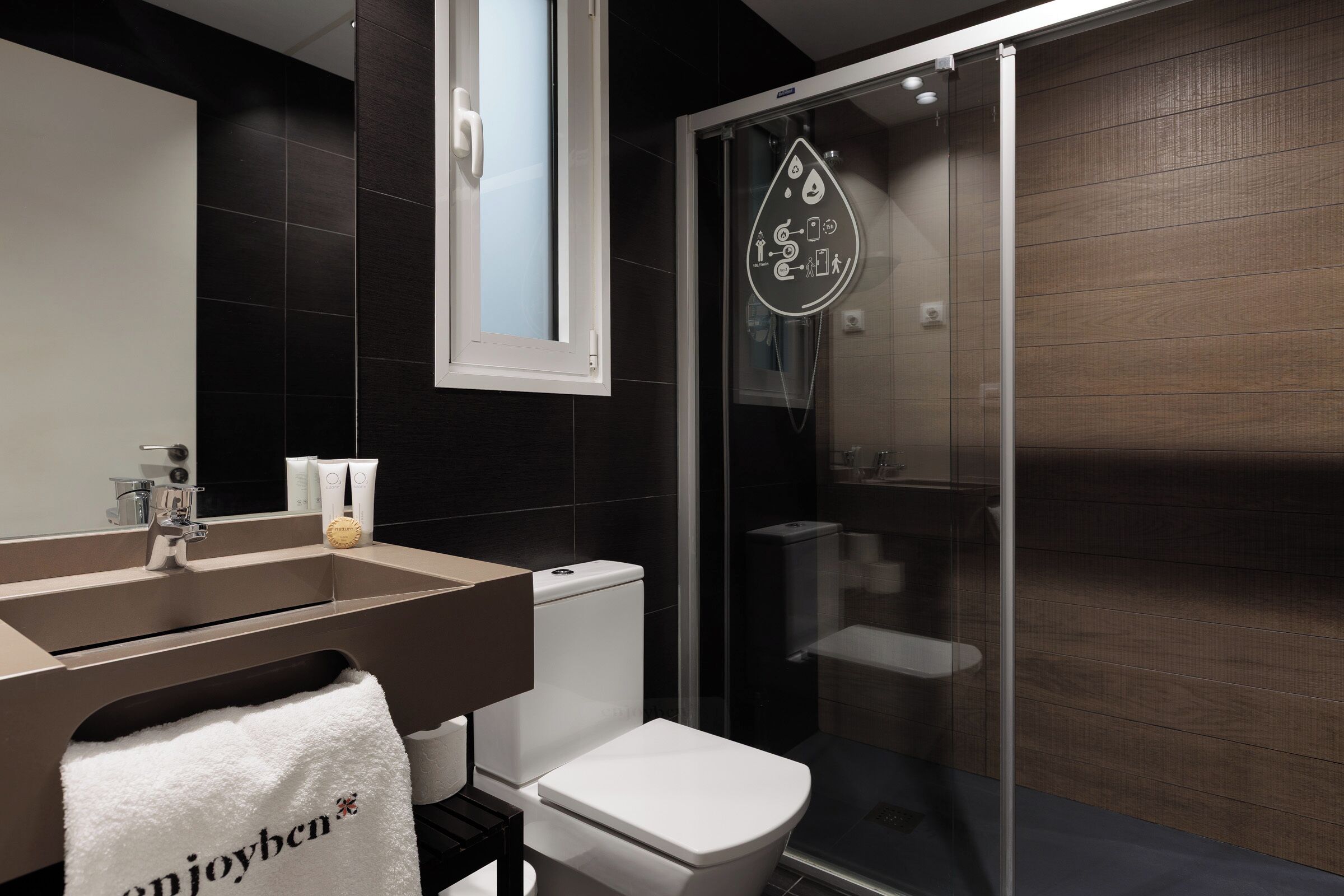 Un baño moderno con lavamanos, inodoro y ducha con mampara de vidrio.