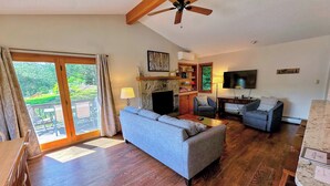 A spacious living room with a sofa, chairs, a fireplace, a television, and a ceiling fan.