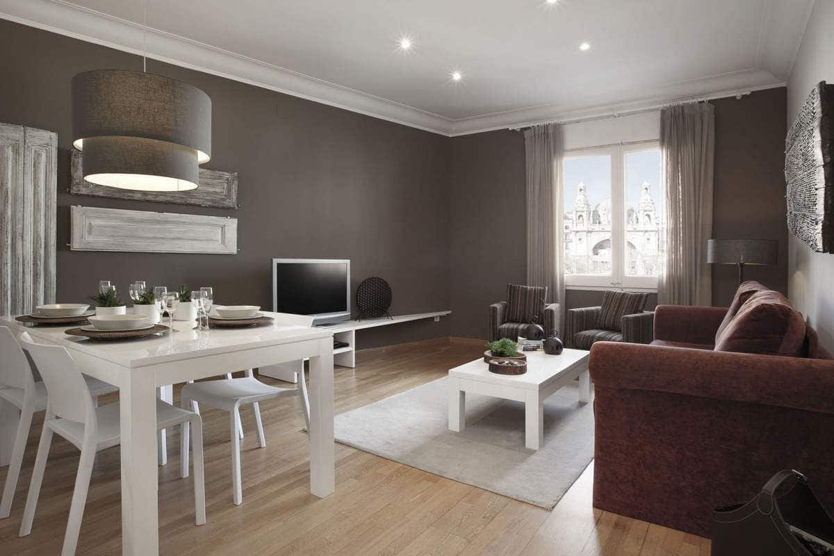 Uma sala de estar moderna com área de jantar, TV de tela plana e uma grande janela com vista para a cidade.
