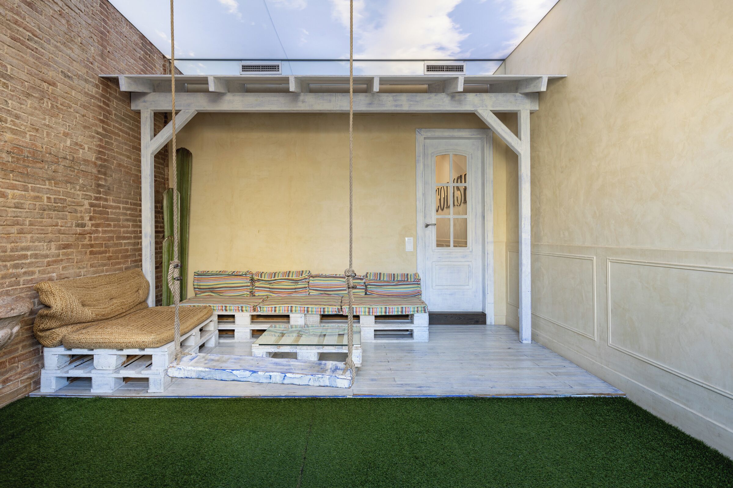 A patio with a swing, a cushioned bench, and a door labeled "COLLIS".