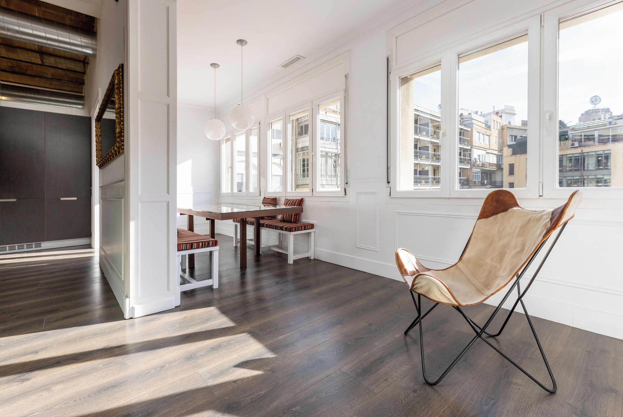 A spacious room with a dining area, large windows, and a view of the cityscape.