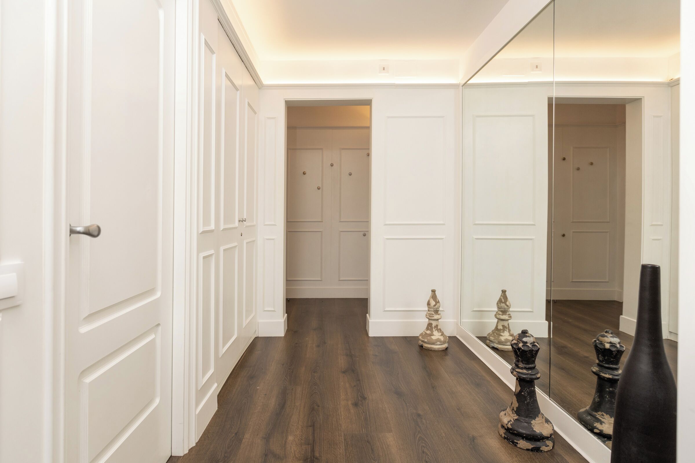 A hallway with white doors and a dark wooden floor.