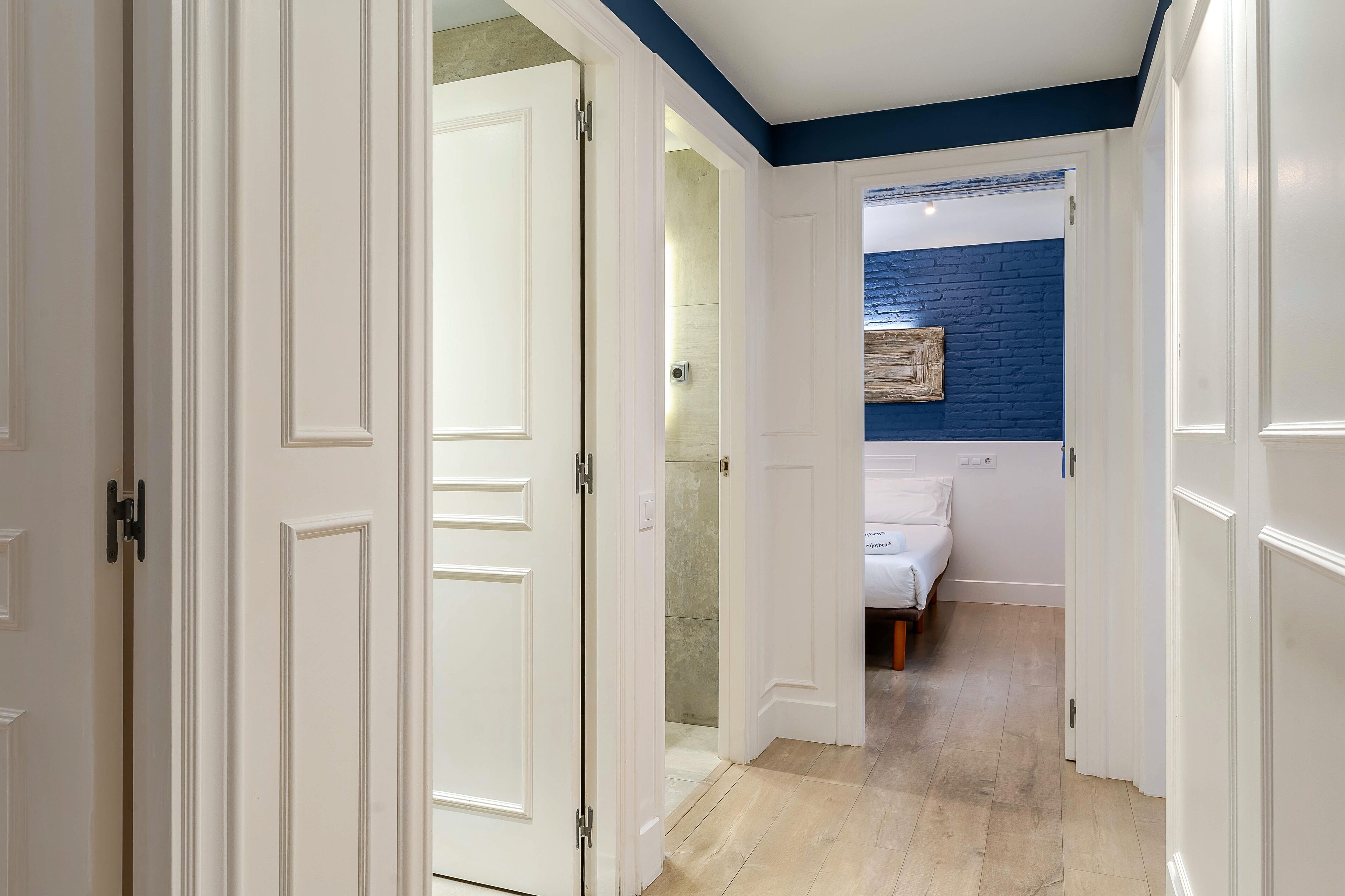 Un pasillo que conduce a un dormitorio con una pared azul decorativa y una cama.