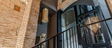A staircase with a wrought iron railing, brick walls, and a large window with a view of the interior.
