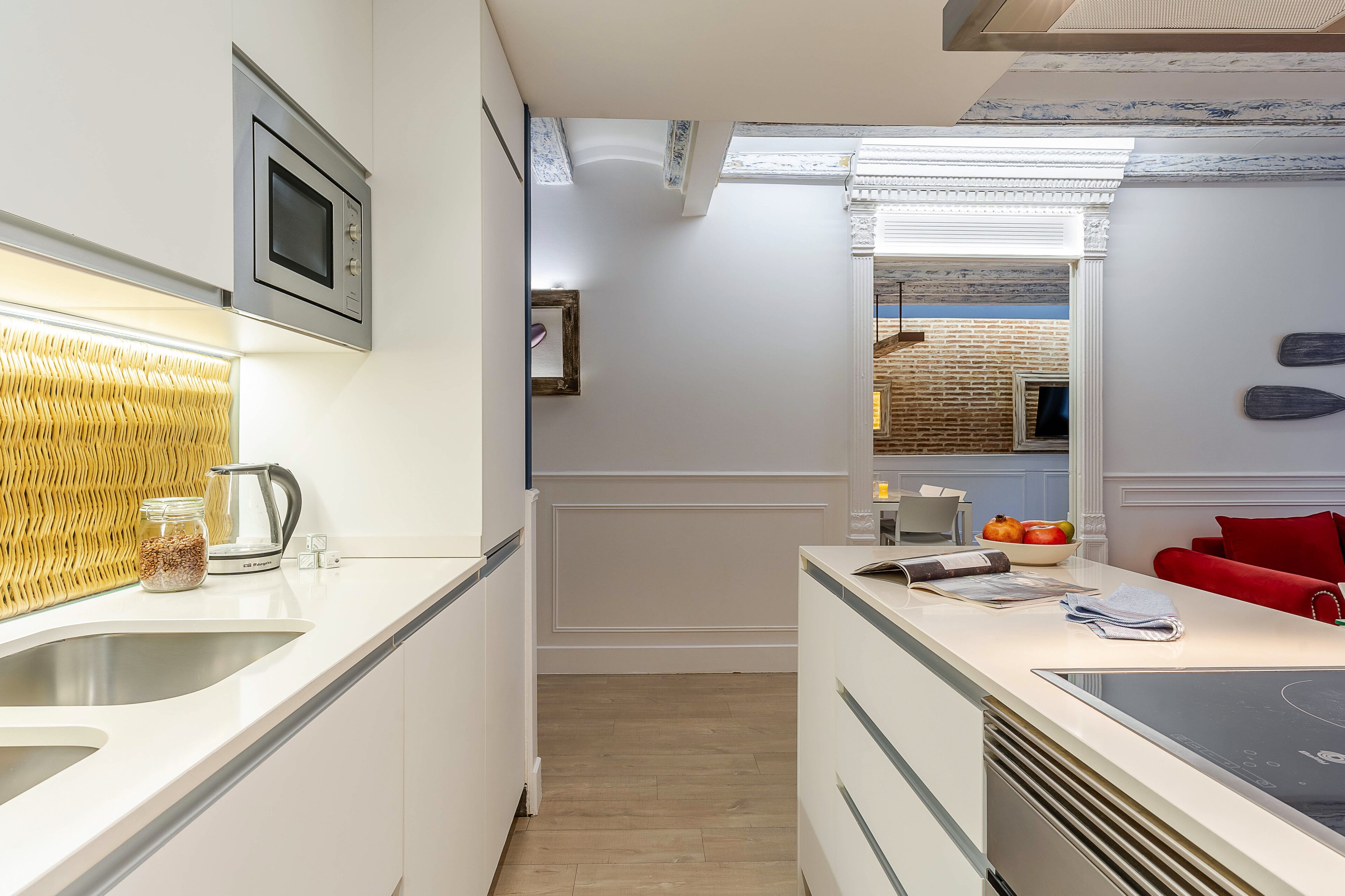 A modern kitchen with a built-in microwave, a kettle, and a sink.
