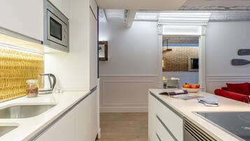 A modern kitchen with a built-in microwave, a kettle, and a sink.