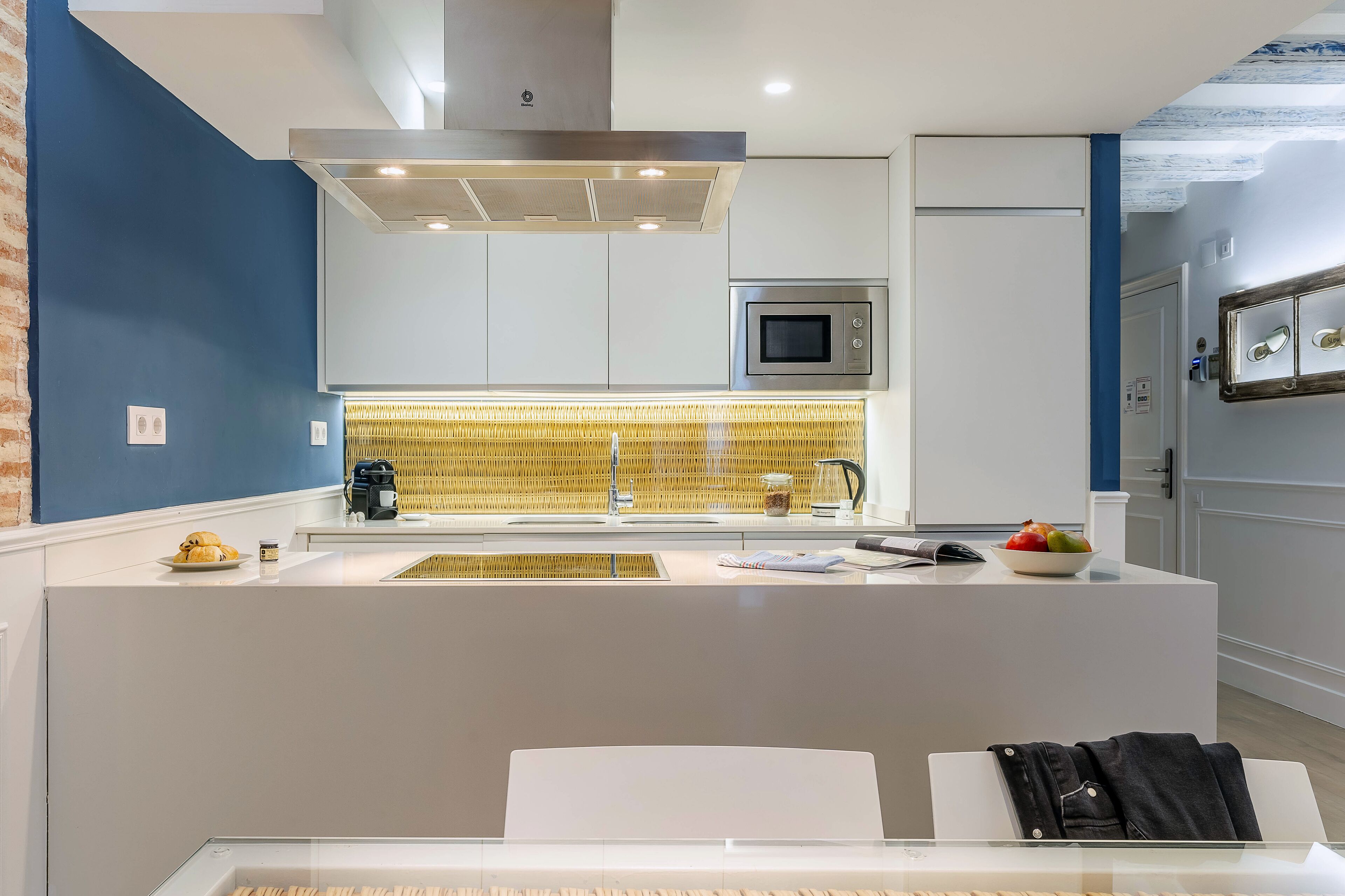 A modern kitchen with a central island, stainless steel appliances, and a unique yellow patterned backsplash.