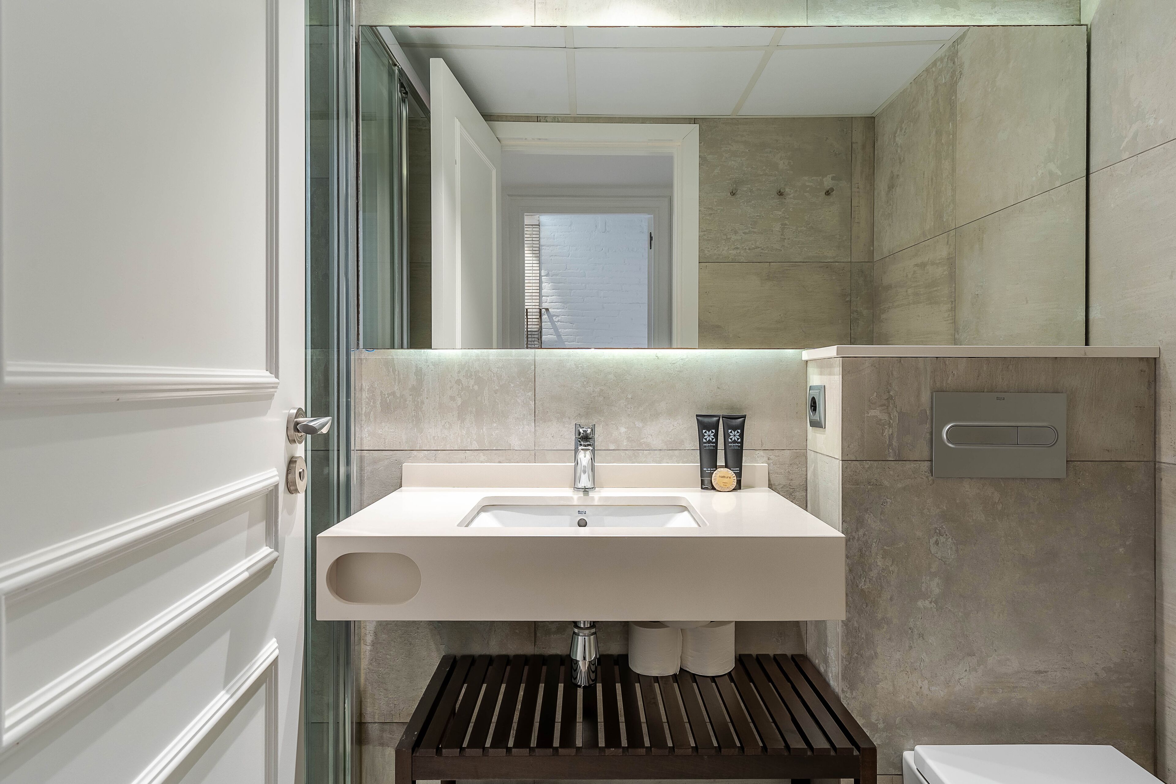 A modern bathroom with a large sink, a mirror, and a toilet.