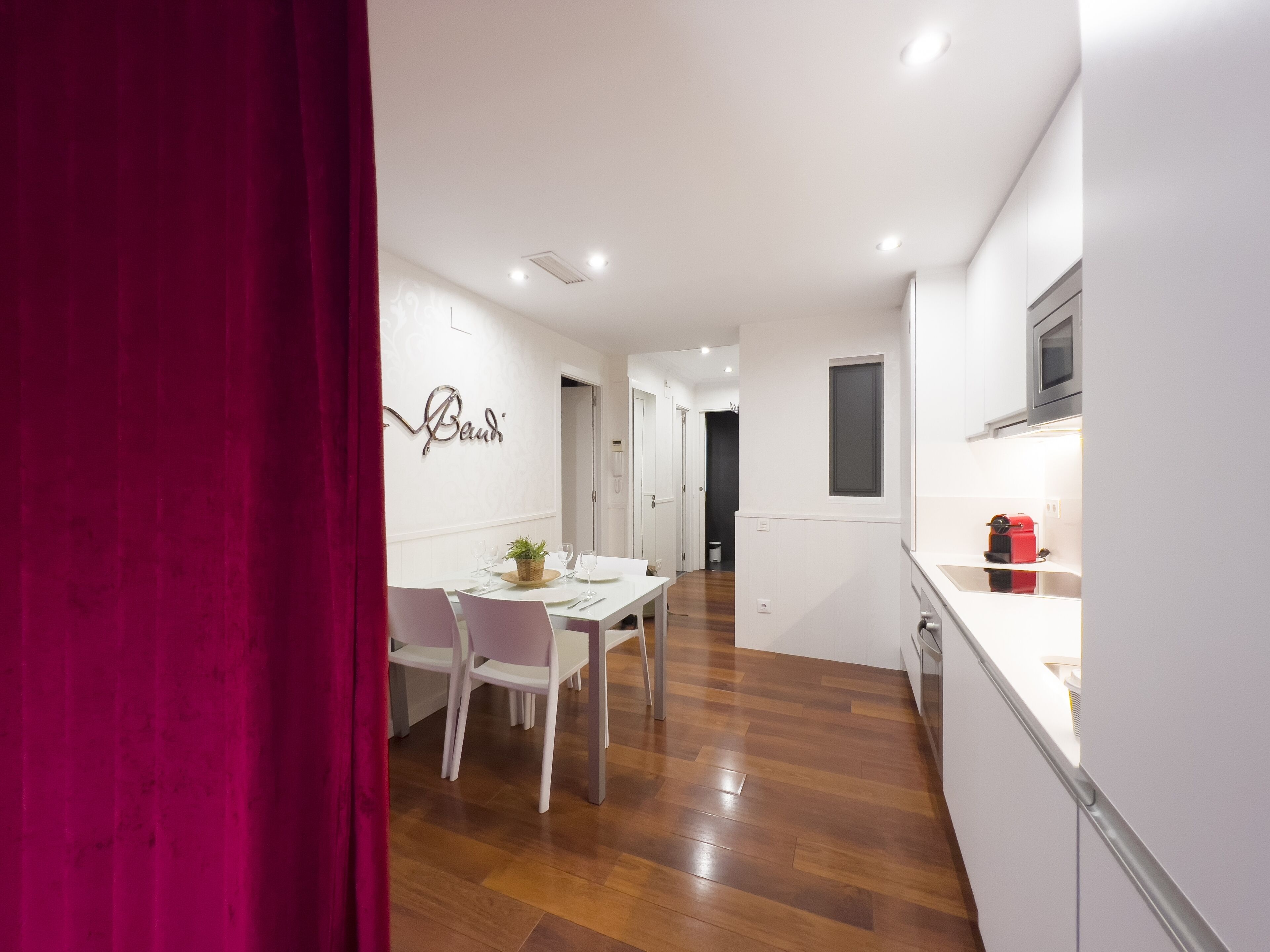 Una cocina moderna con armarios blancos, un microondas y un tostador rojo.