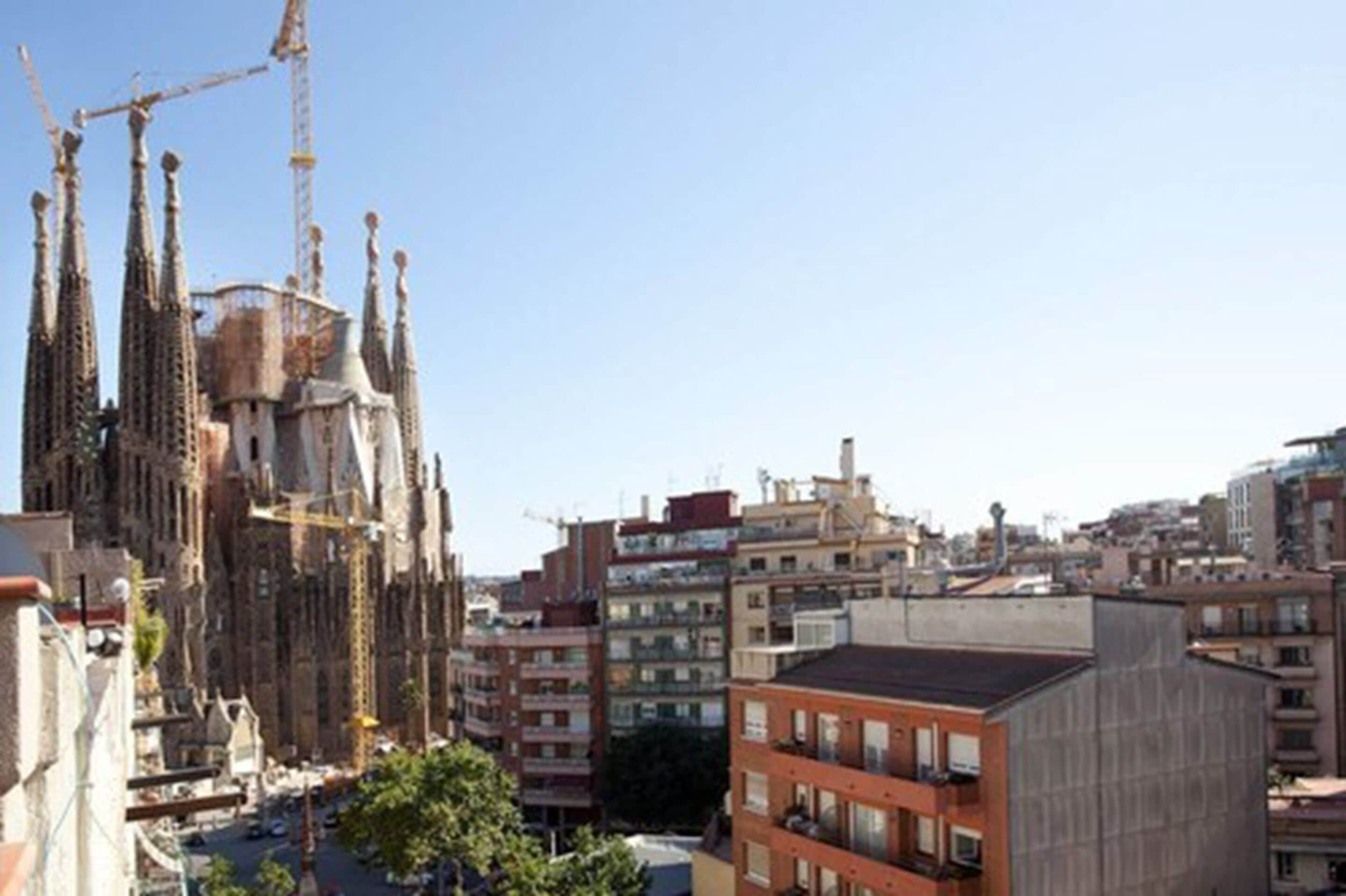 A cityscape with a prominent cathedral featuring Gothic architecture, surrounded by residential buildings and construction cranes.
