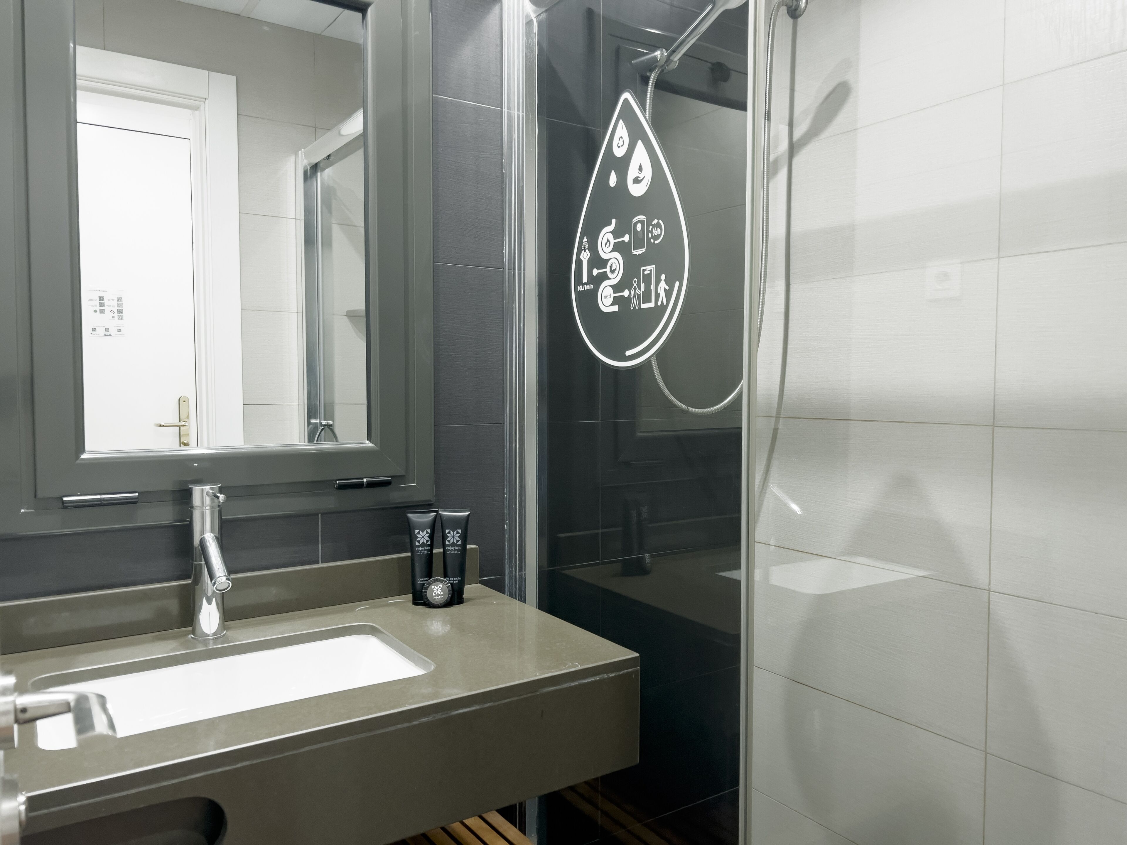 A modern bathroom with a large mirror, a sink, and a shower area.
