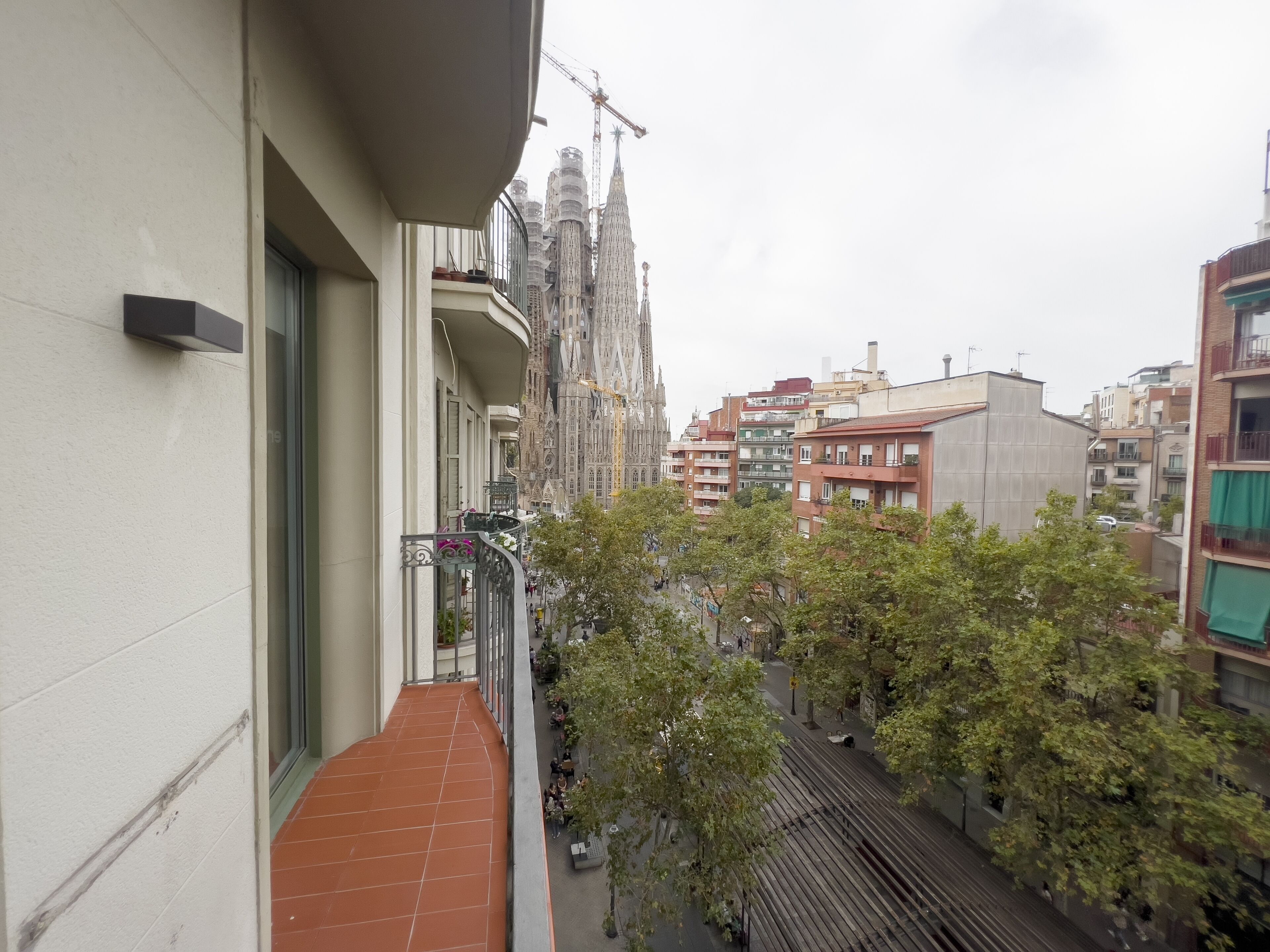 Un balcon offrant une vue sur le paysage urbain, avec notamment un bâtiment historique doté d’une flèche et des immeubles résidentiels modernes.