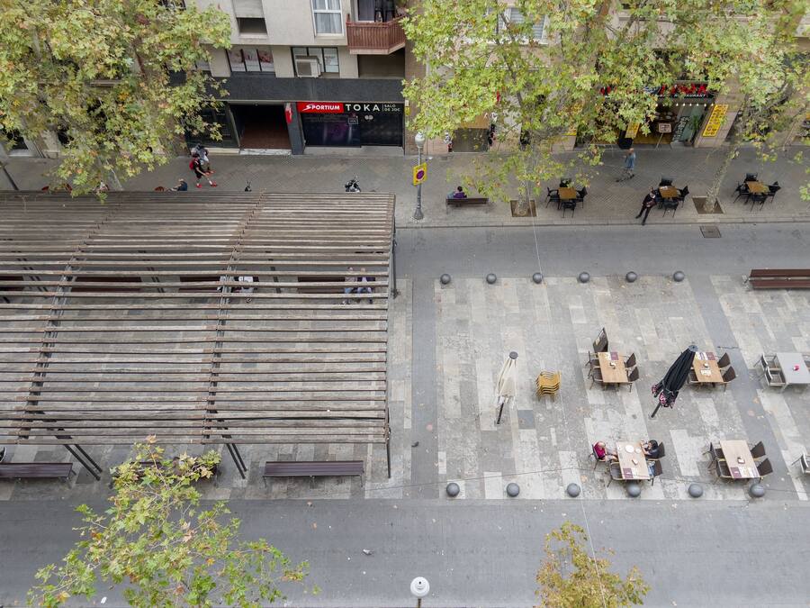 Vista de la calle con un restaurante llamado 'Sportium Toka' y una cafetería con terraza.