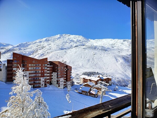 A modern building with multiple floors and balconies, surrounded by snow-covered mountains.