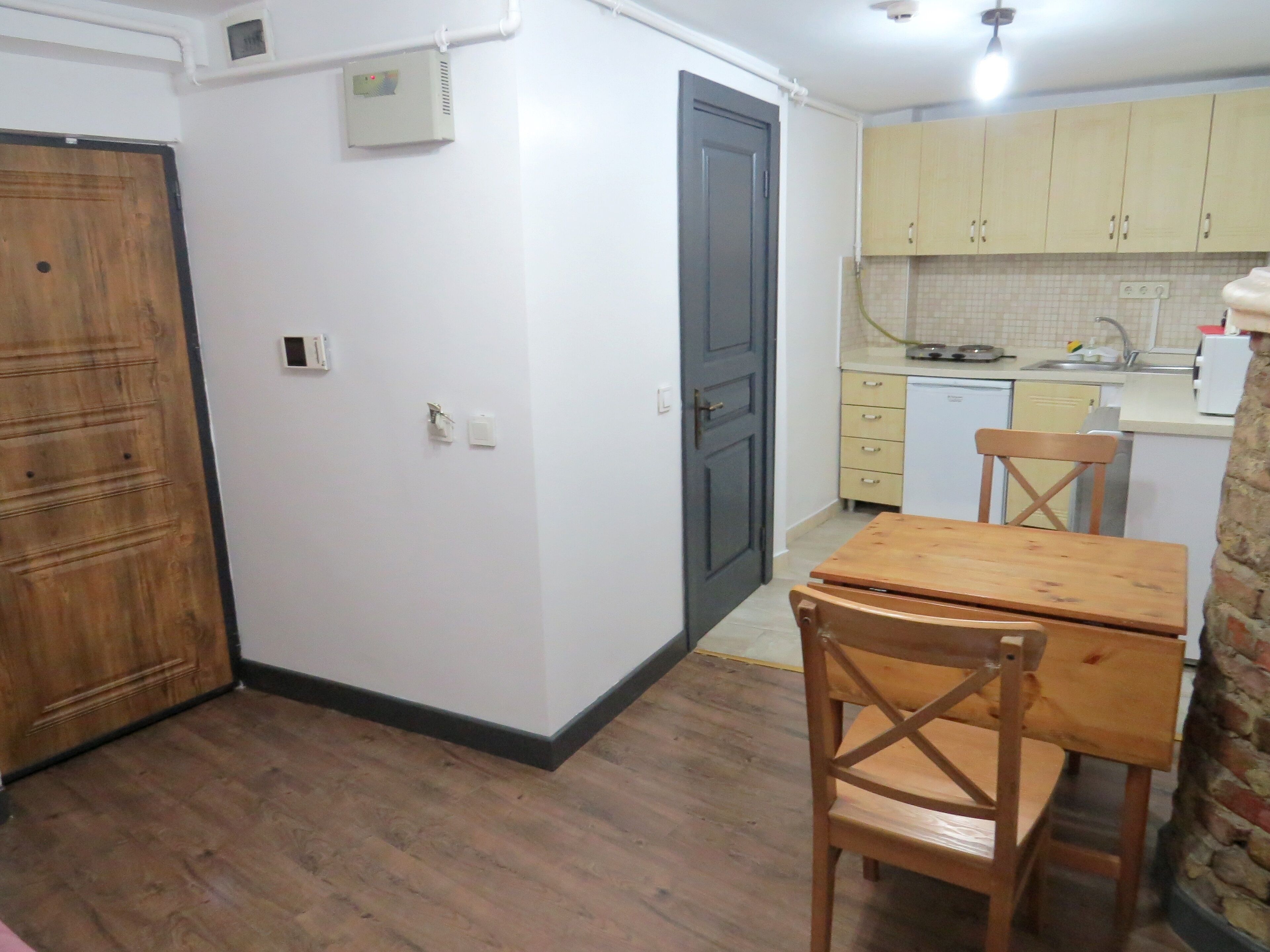 A compact kitchen with wooden cabinets, a small dining table, and a chair.