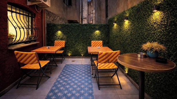Un espace extérieur aménagé avec des tables et des chaises, un tapis à motifs bleus et un mur végétal.