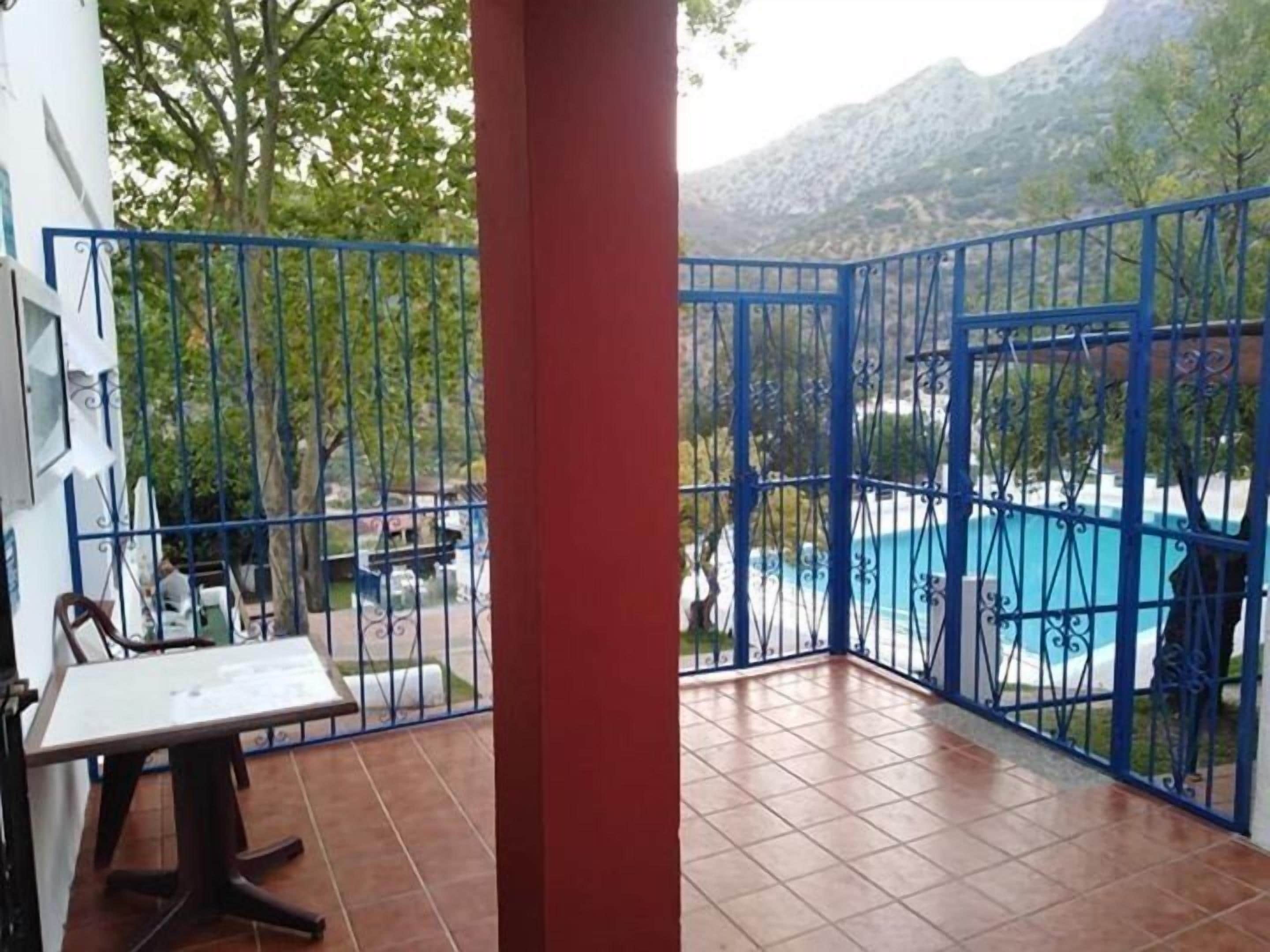 A balcony with a view of a swimming pool and mountains.
