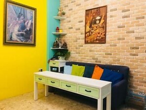 Une pièce avec un canapé bleu, une table blanche et un mur jaune.