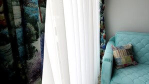 A room with a teal sofa, a colorful cushion, and patterned curtains. - Istanberry - Dream Apartments (Istanbul)