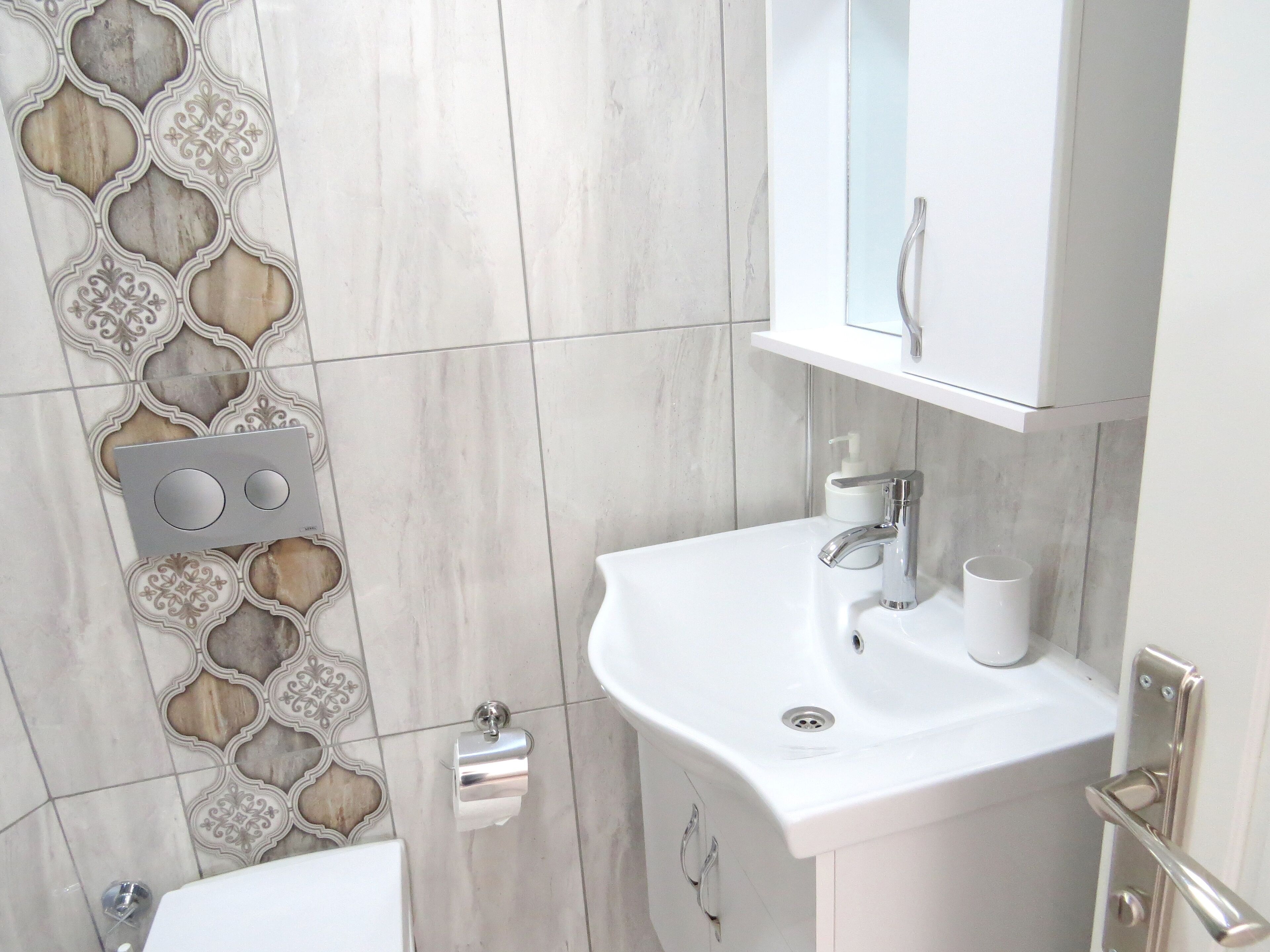 A bathroom with a white sink, a mirror above it, and a toilet.