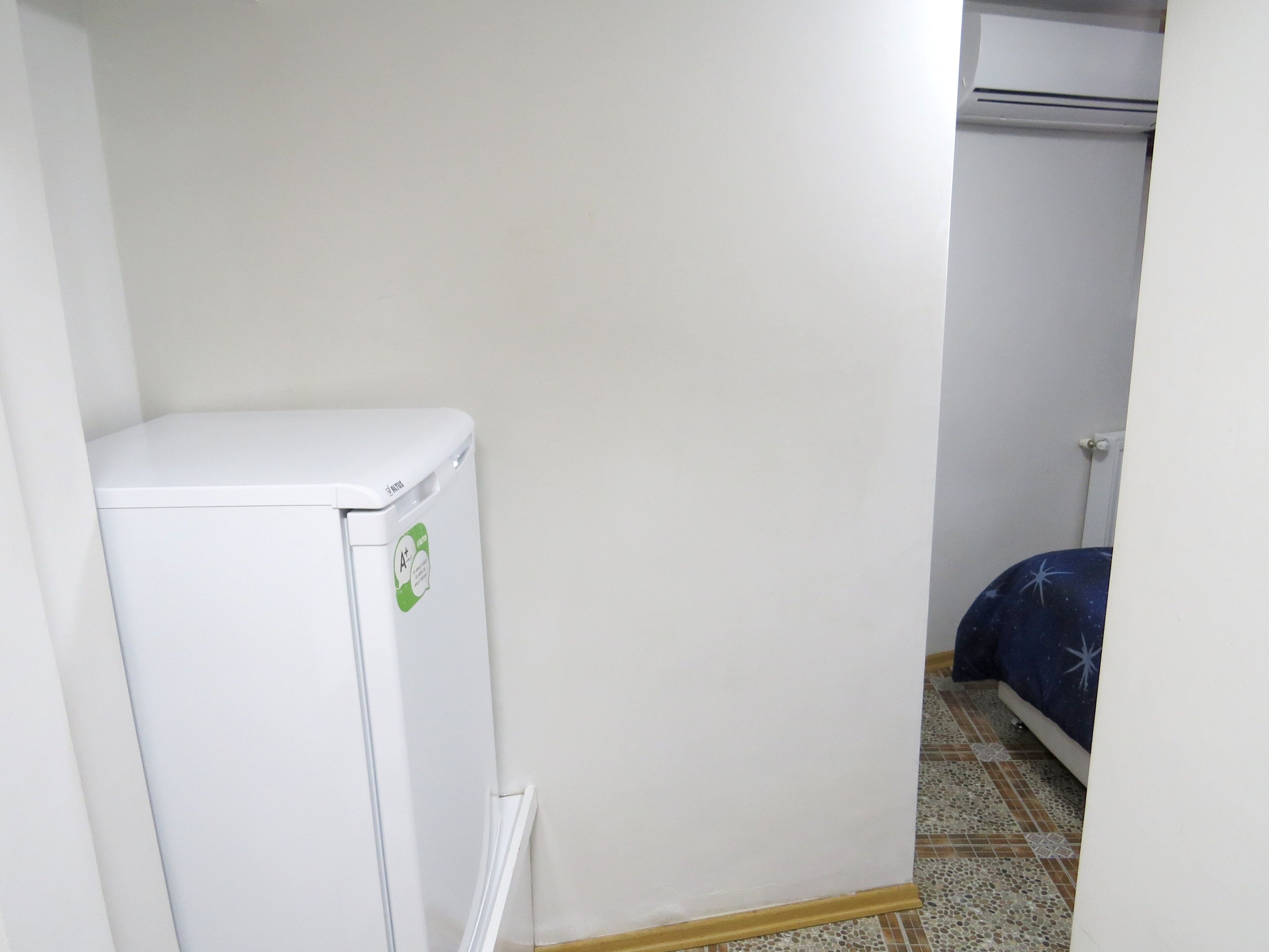 A small, white refrigerator with a sticker indicating energy efficiency.