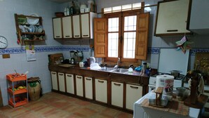 A kitchen with wooden cabinets, a sink, and a window. - Casa Guarrios, well tailor. Number 7 (Moratalla)
