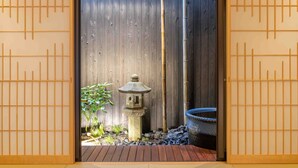 Un jardin japonais traditionnel, agrémenté d’une clôture en bois, d’une lanterne en pierre et d’un grand pot noir.