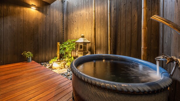 Un espace de détente en bois comprenant un bain à remous, une lanterne en pierre et un petit jardin.