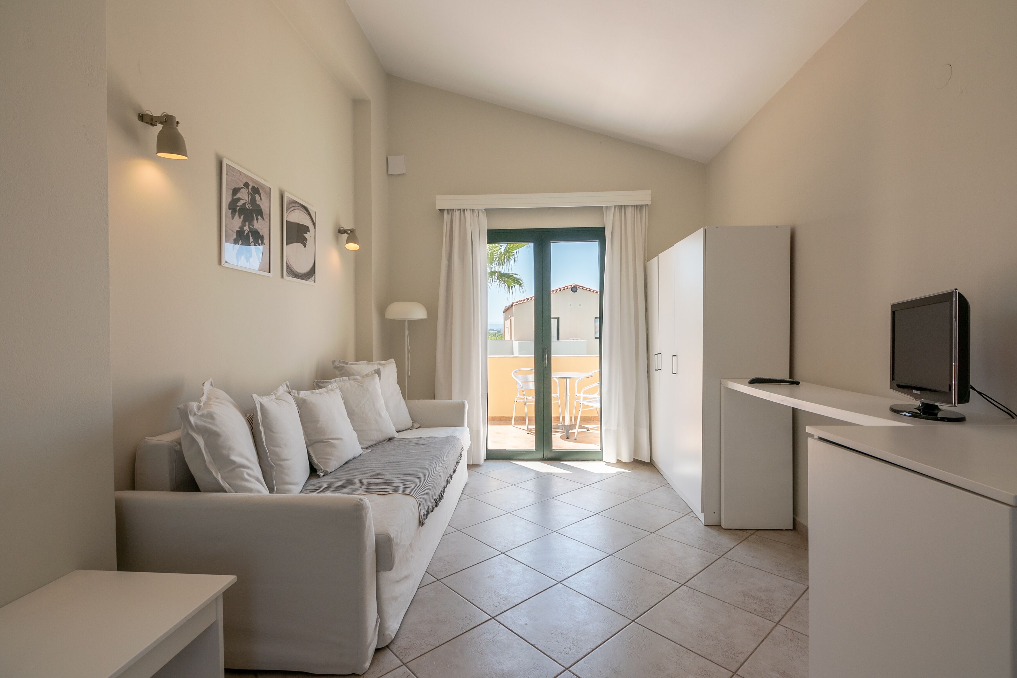 Una sala de estar moderna y minimalista con un sofá, un televisor de pantalla plana y una zona de comedor con una mesa y sillas.
