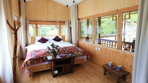 Una habitación de madera con una cama, una mesita y ventanas.