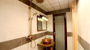 A bathroom with a shower, a sink with a wooden countertop, and a mirror with lights.