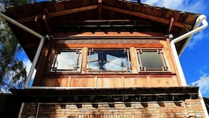 Un edificio de madera de dos plantas con base de ladrillo y un balcón.
