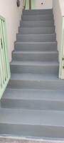 Unos escalones grises con una barandilla verde claro a la izquierda.