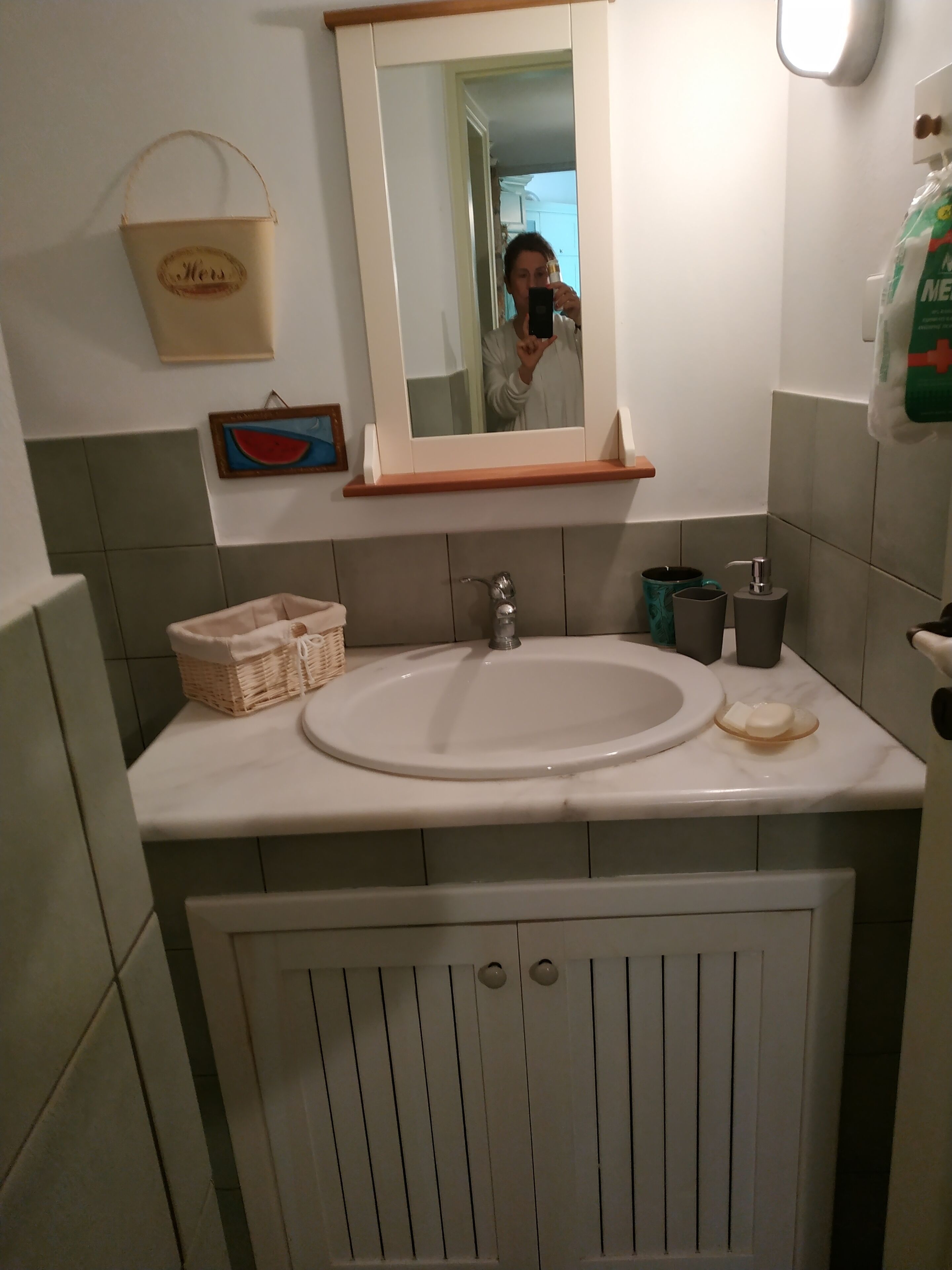 A bathroom with a white sink, a mirror, a basket, and a towel rack.