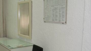 Een steriele ruimte met een bureau, een stoel, een wandtelevisie en een prikbord.
