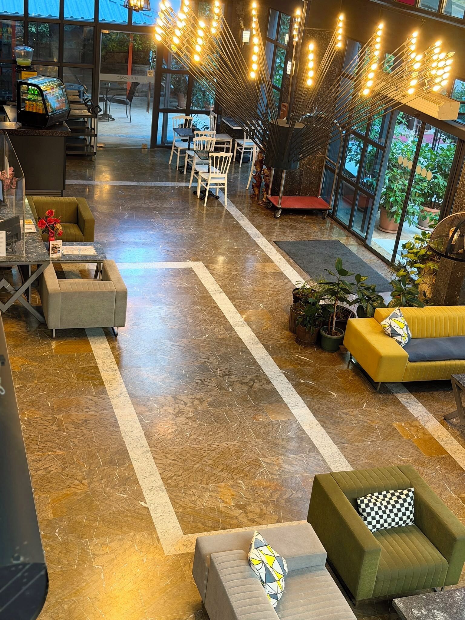 A spacious lobby with seating areas, a reception desk, and a large window providing a view of the outdoors.