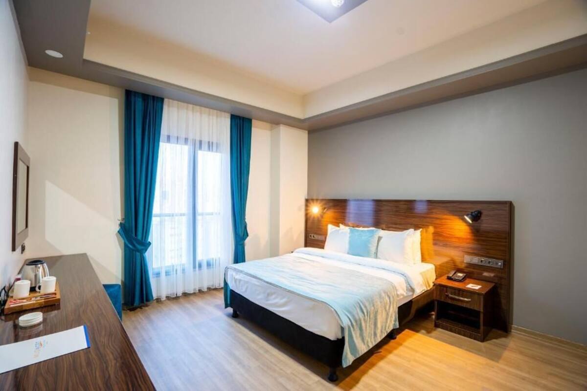 Hotellihuone, jossa on sänky, yöpöytä ja työpöytä sekä kahvinkeitin.