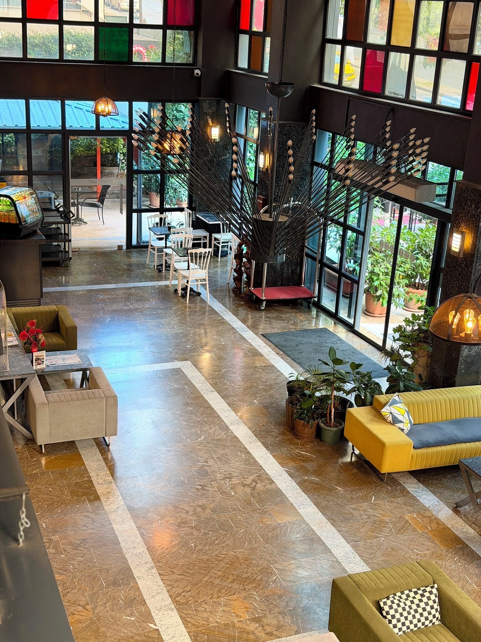 A spacious lobby with a modern design, featuring a central seating area with sofas and chairs, a patterned floor, and large windows offering views of the outdoors.