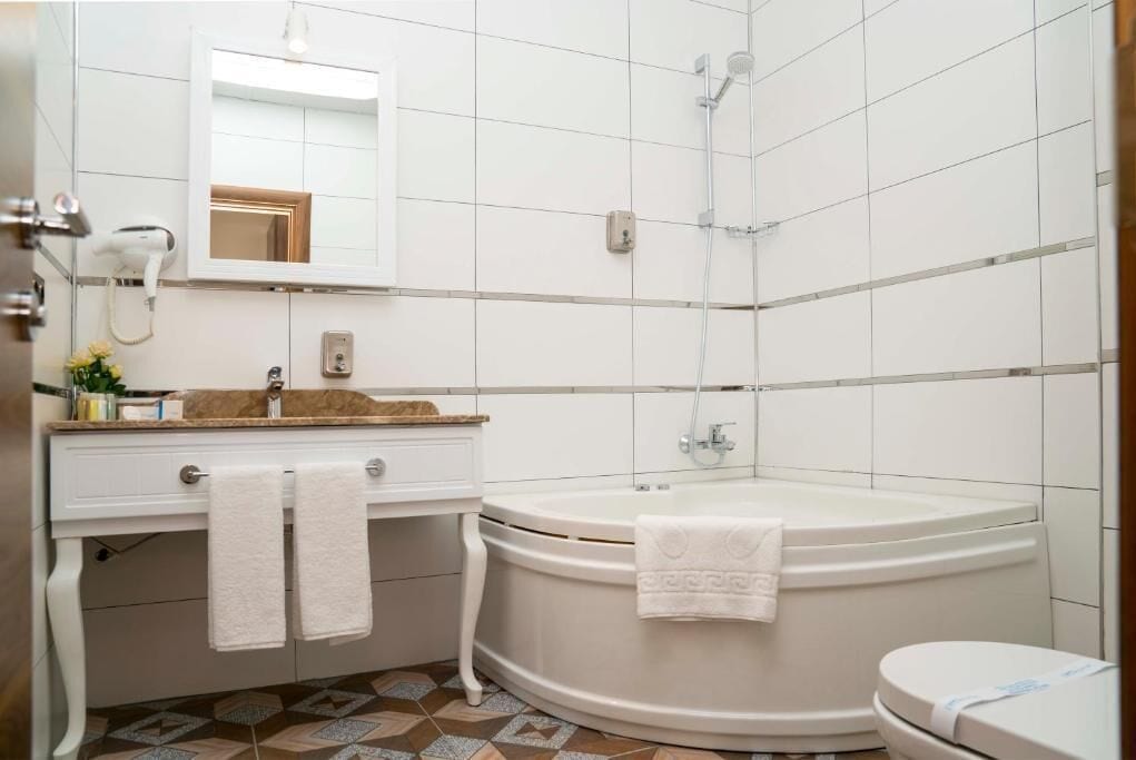 Un baño con tocador blanco, una bañera grande, inodoro y zona de ducha.