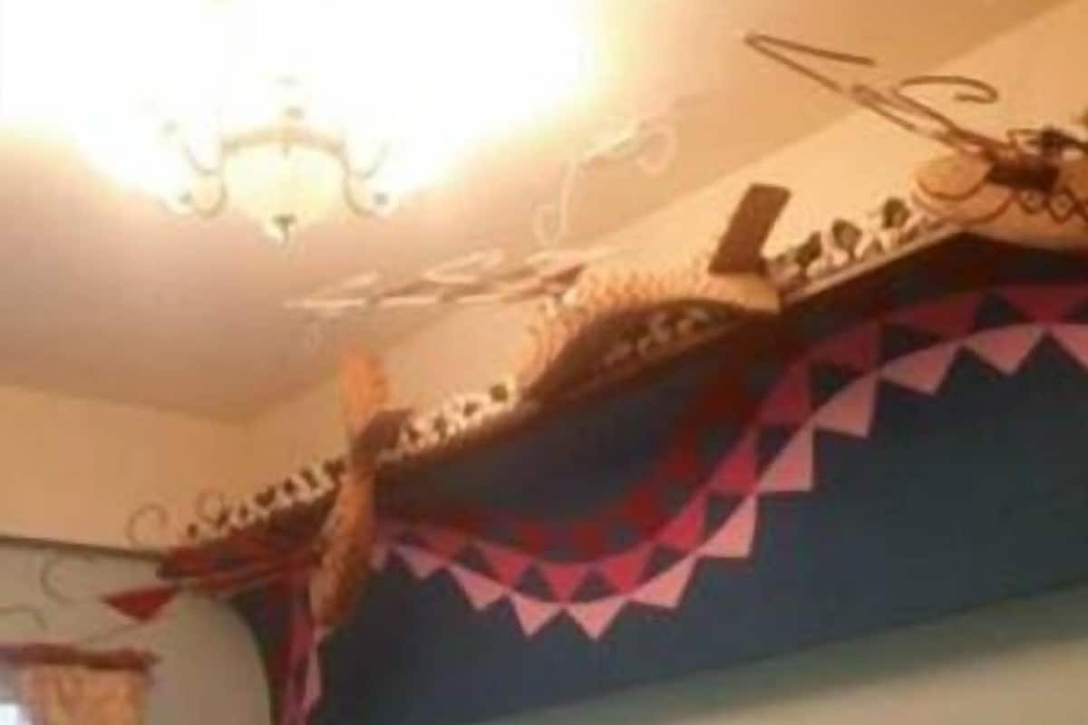 A room with a bed, a window with curtains, and a decorative ceiling.