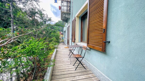 Uma passagem de madeira estreita que leva a um edifício com varanda.