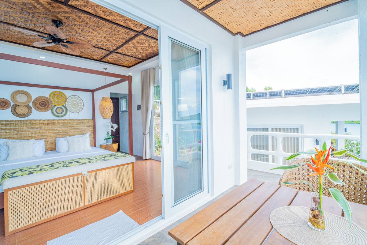 A bedroom with a bed, a ceiling fan, and a view of the outdoors.
