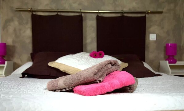 A neatly made bed with a white comforter, a brown pillow, and a pink towel. - Domaine du Siestou Wine Resort & Spa (Laure-Minervois)