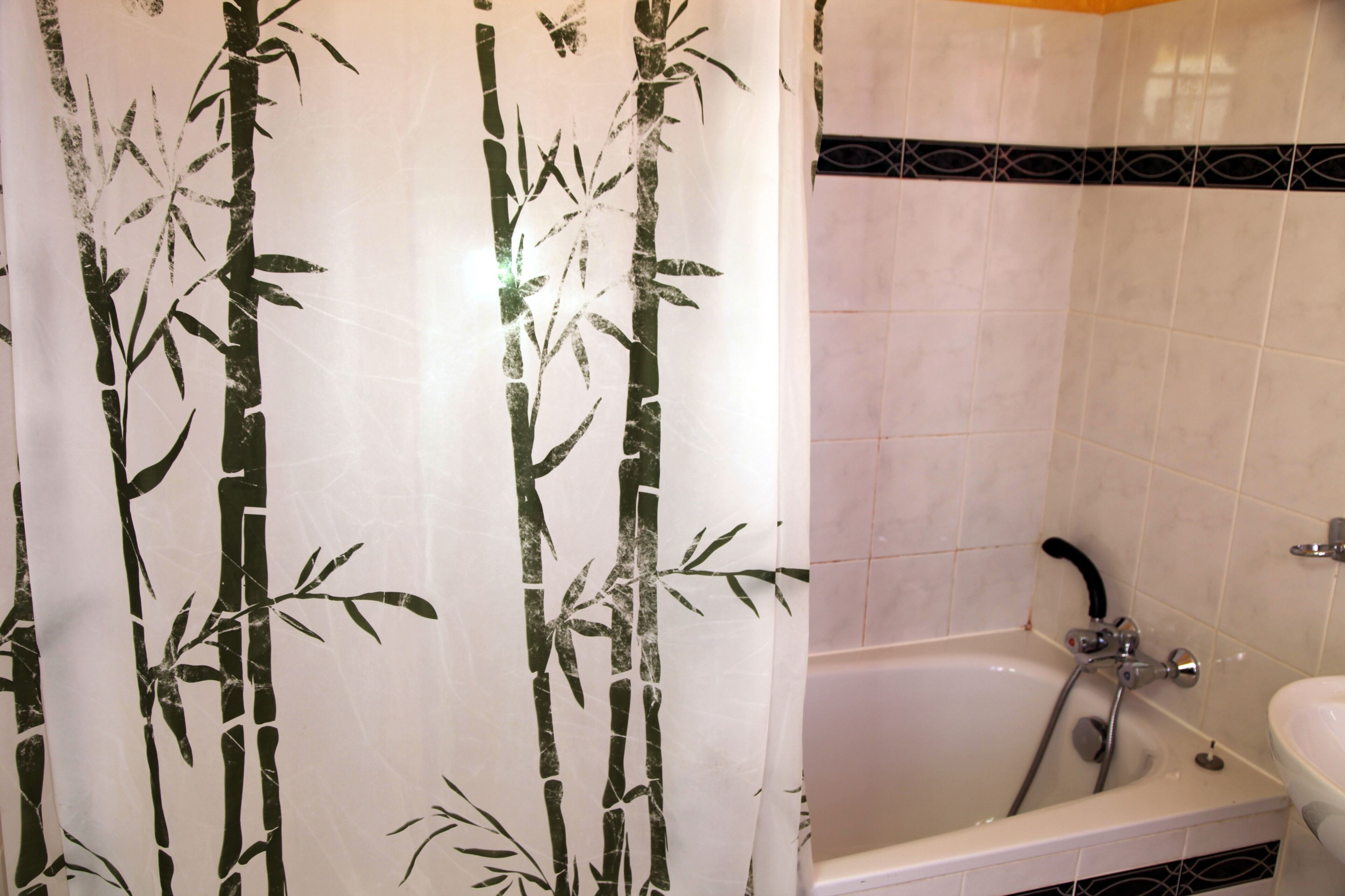 A bathroom with a bamboo-themed shower curtain, a bathtub, and a sink.