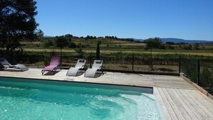 A poolside area with lounge chairs and a view of a vineyard. - Domaine du Siestou Wine Resort & Spa (Laure-Minervois)