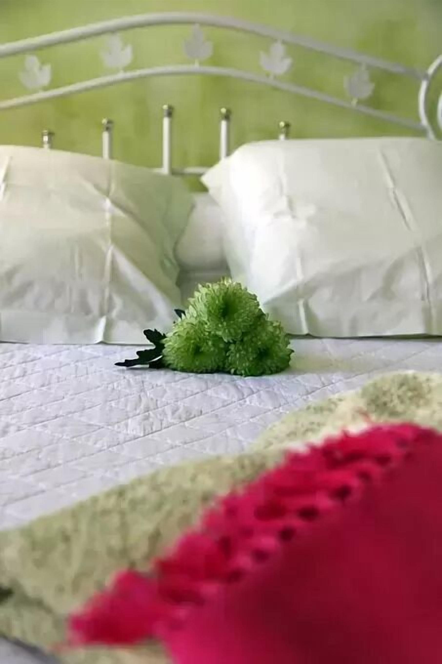 A bed with a green headboard, white bedding, and a green decorative item on the bed.